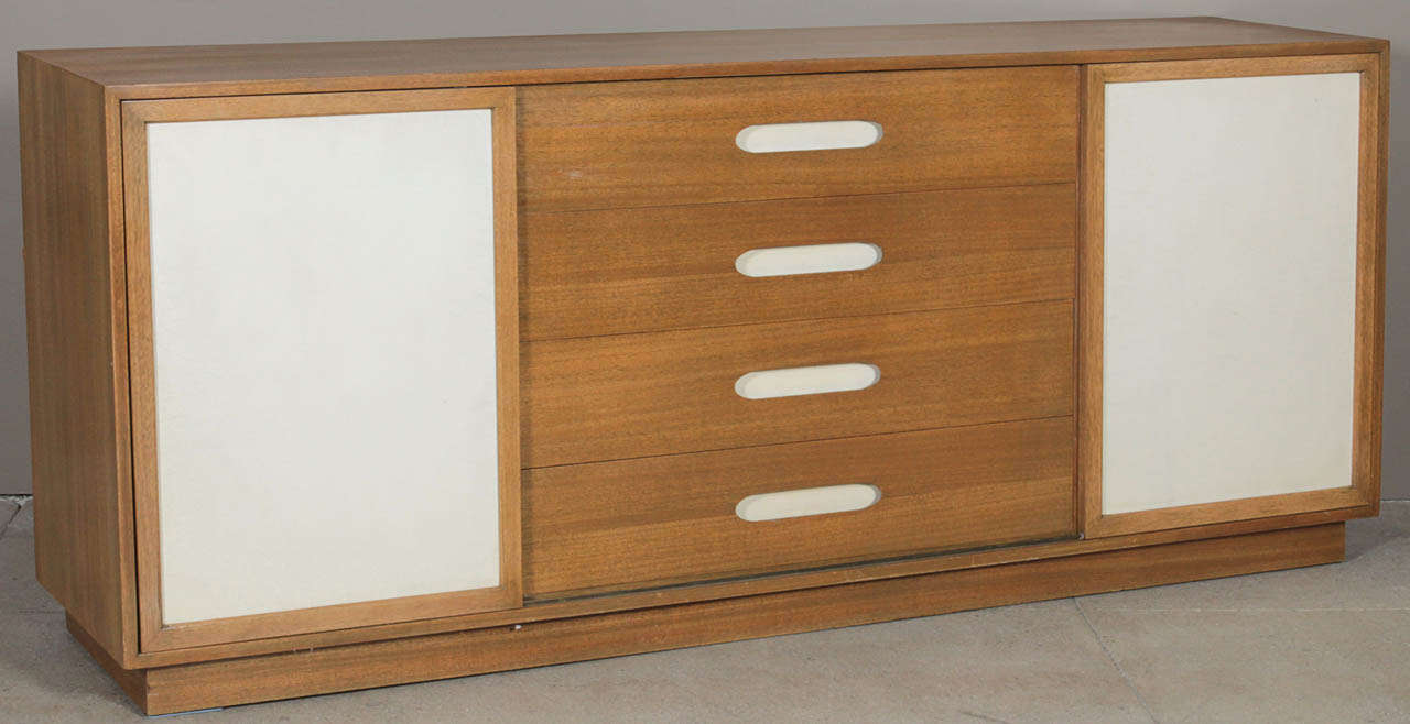 Light mahogany four drawer sideboard with two white leather sliding doors opening to reveal white lacquer drawers to the left side, white lacquer slides with cork surface (keeping plates or glassware from slipping) to the right side. Beautifully